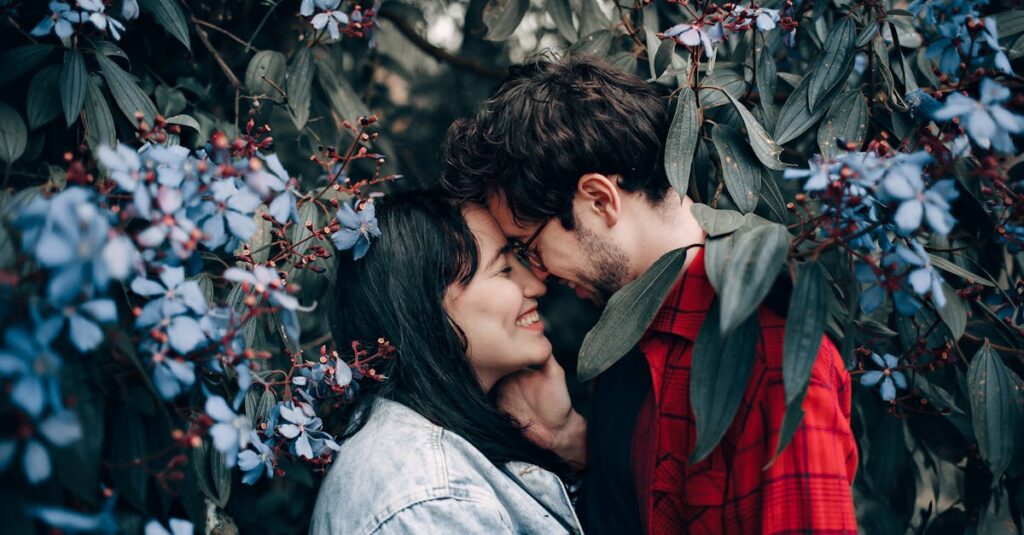 Happy couple sharing a romantic moment surrounded by beautiful blue flowers.