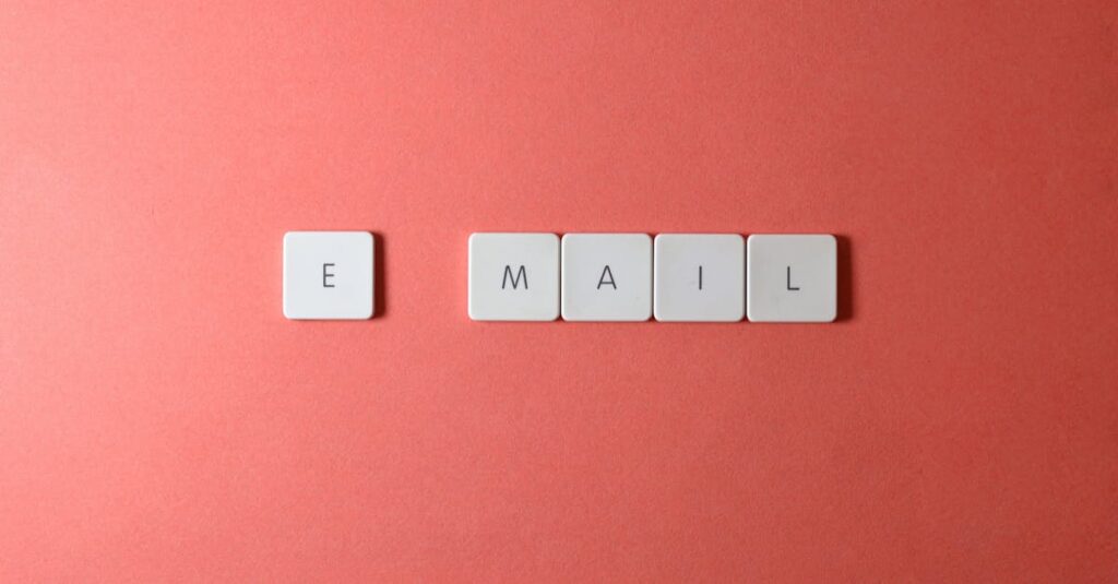 Flat lay of keyboard letter tiles spelling 'email' on coral backdrop.